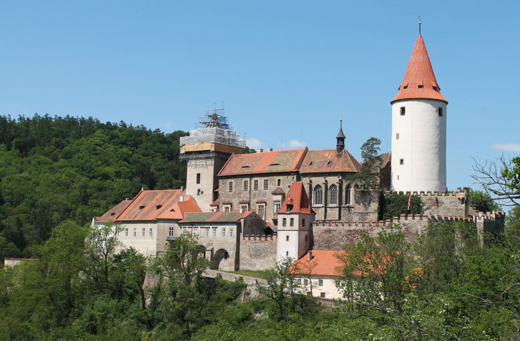 Pohled na hrad Křivoklát obklopený hustými lesy a řekou Berounkou