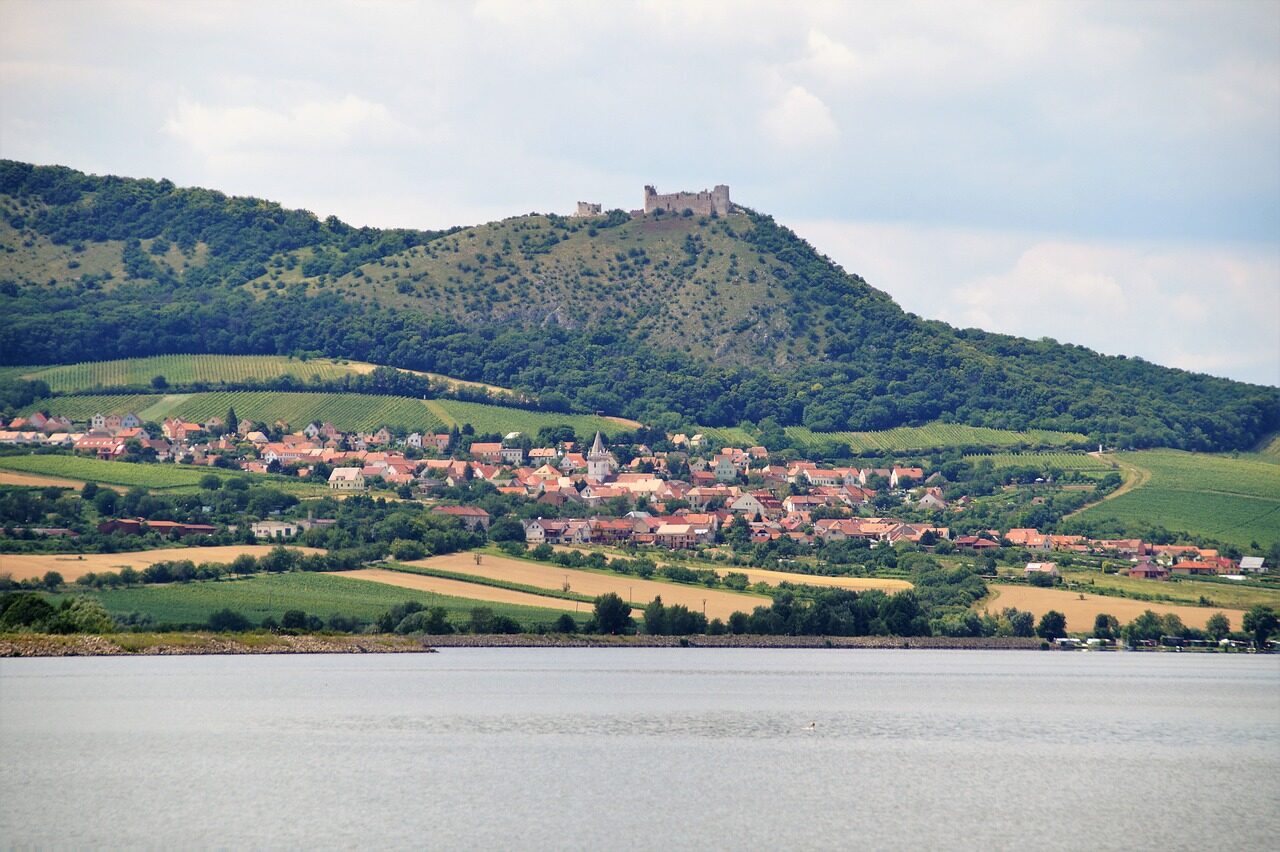 Skalní zřícenina hradu Děvičky tyčící se nad vodní nádrží Nové Mlýny a vinařskou obcí Pavlov